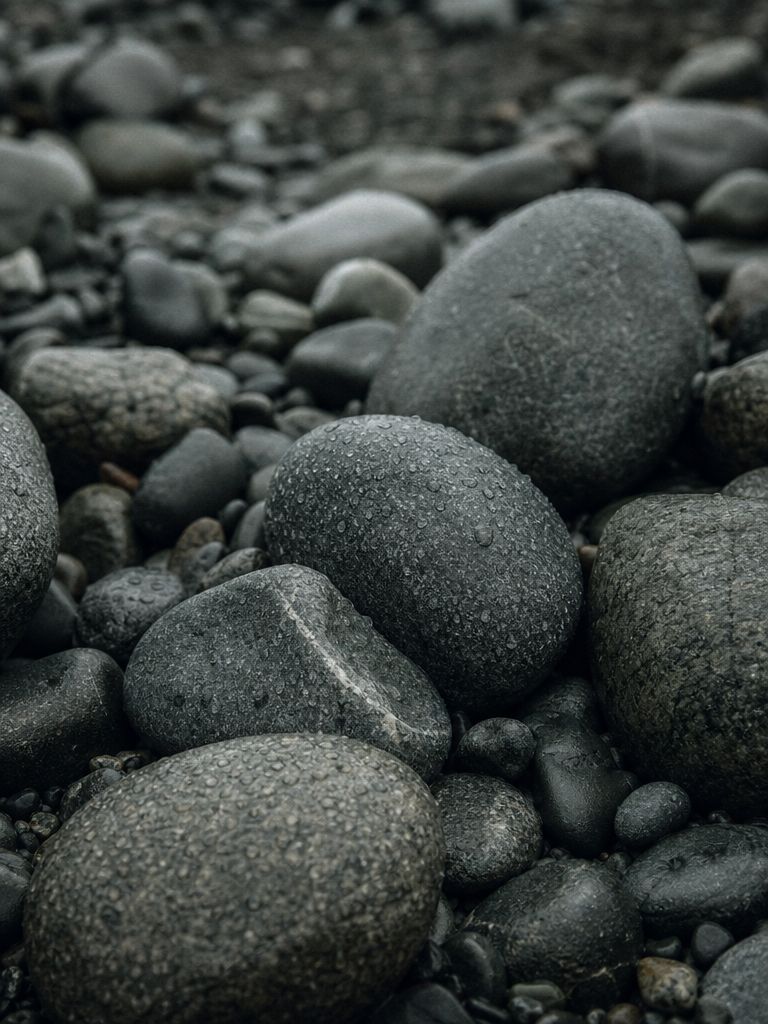 Dark river stones in a natural pile, covered in water droplets