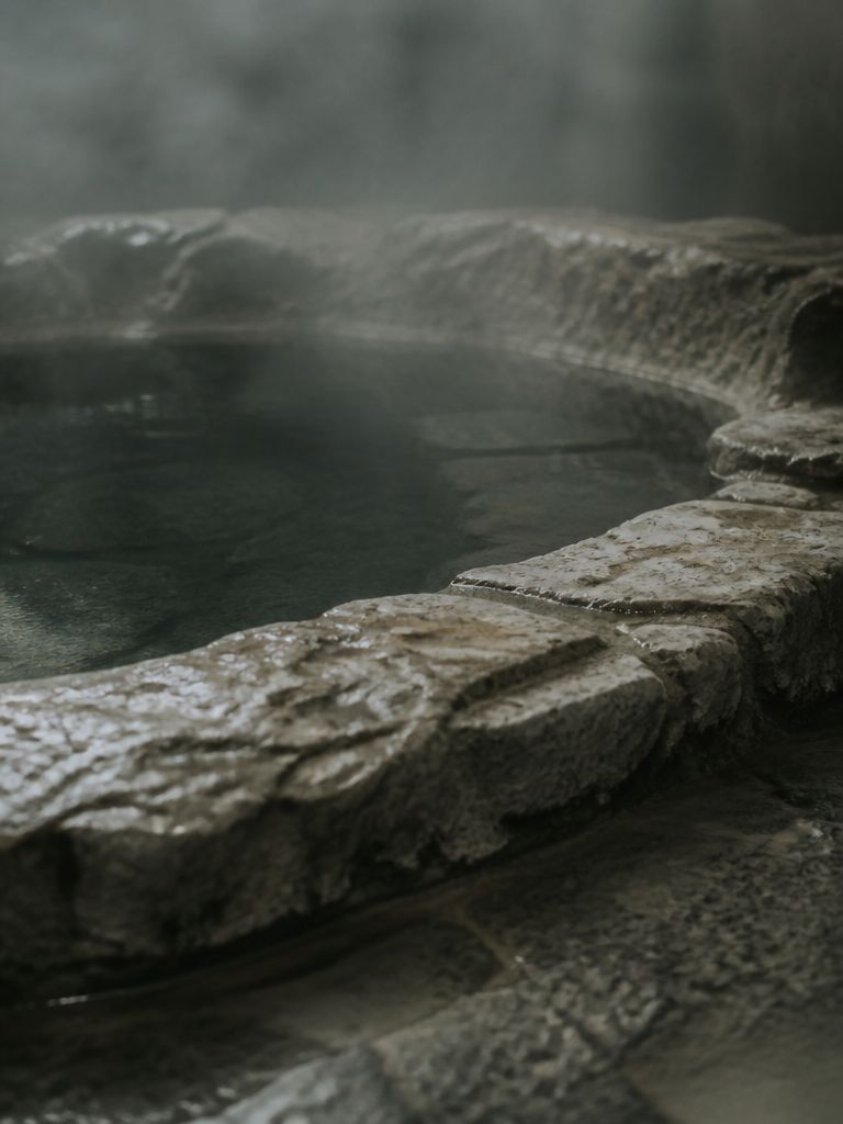 Still dark water in a stone bath with faint steam